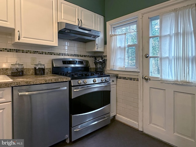 kitchen with appliances with stainless steel finishes, white cabinets, under cabinet range hood, and decorative backsplash