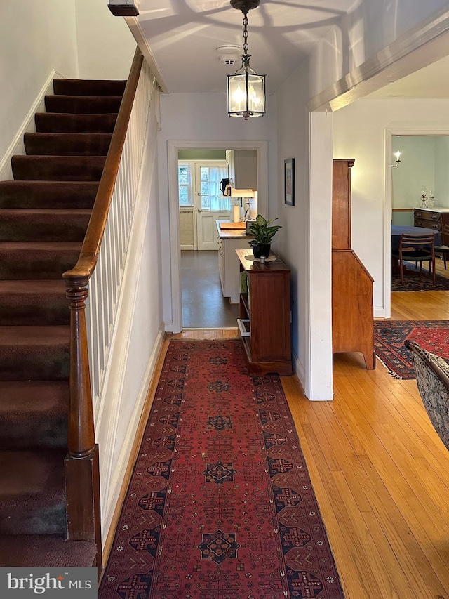 hall with baseboards, stairway, and hardwood / wood-style floors