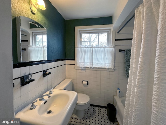 full bath featuring wainscoting, a sink, tile walls, and toilet