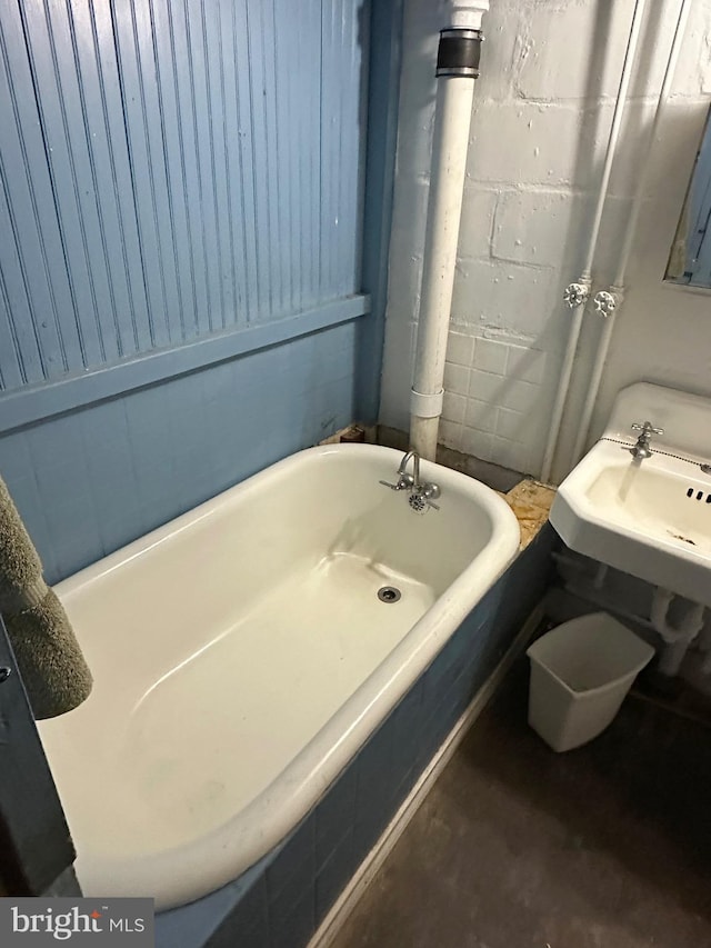 full bath with concrete block wall and a washtub