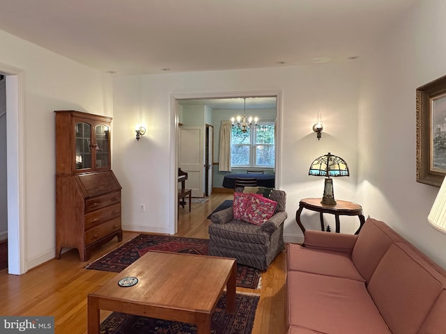 living room with a chandelier, light wood-type flooring, and baseboards