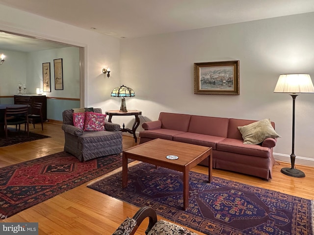 living room with a chandelier, baseboards, and wood finished floors