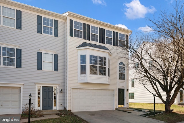 townhome / multi-family property with metal roof, an attached garage, driveway, and a standing seam roof