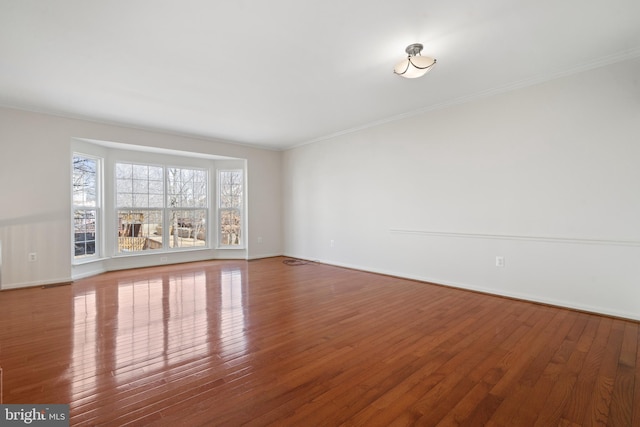 empty room featuring baseboards, ornamental molding, and hardwood / wood-style flooring