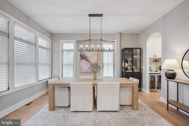 dining room with light wood finished floors, wine cooler, and baseboards