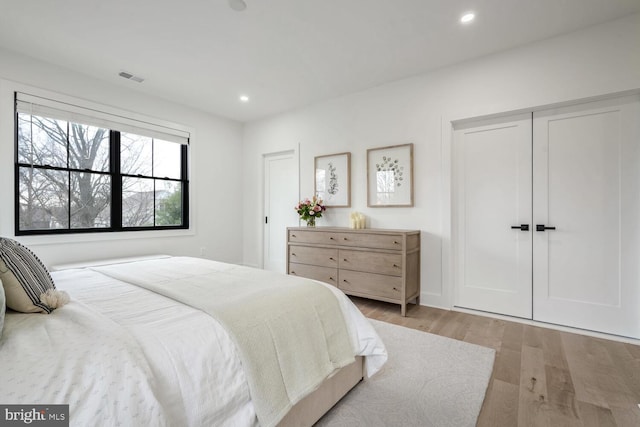 bedroom with light wood-type flooring, visible vents, a closet, and recessed lighting