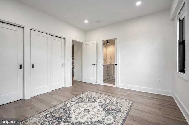 bedroom featuring recessed lighting, wood finished floors, two closets, and baseboards