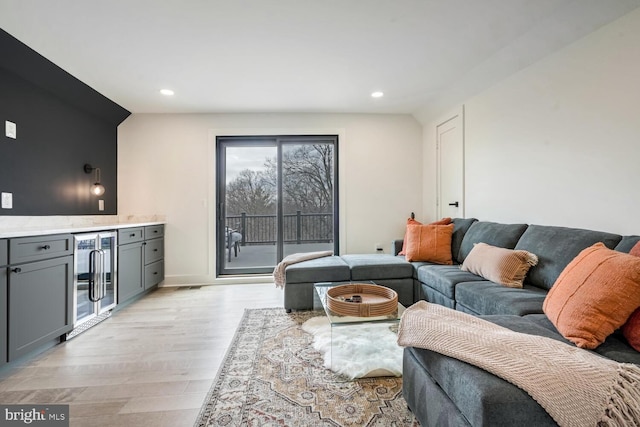 living room featuring a dry bar, light wood finished floors, baseboards, wine cooler, and recessed lighting