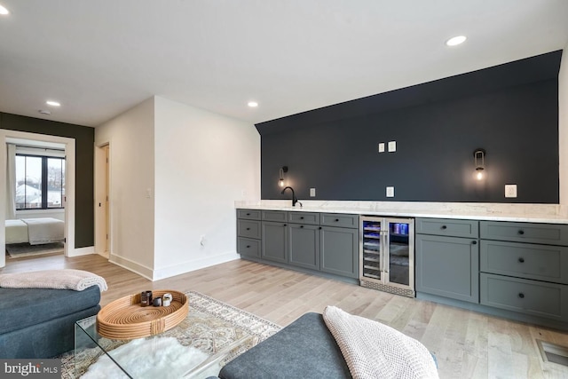 bar featuring beverage cooler, indoor wet bar, a sink, and light wood-style flooring