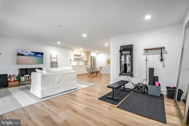 exercise room with light wood finished floors, a sink, and recessed lighting