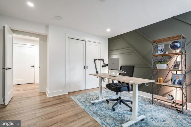 office area with light wood-style flooring, a decorative wall, and recessed lighting