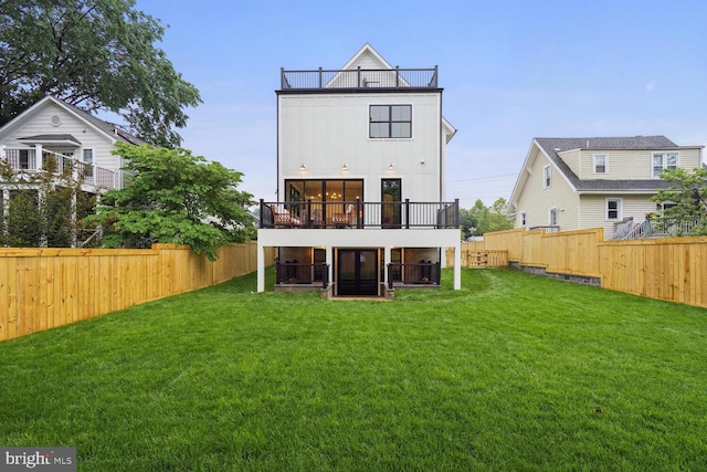 back of house with board and batten siding, a fenced backyard, and a lawn