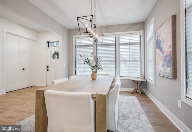 dining space featuring baseboards, light wood-type flooring, a chandelier, and a healthy amount of sunlight