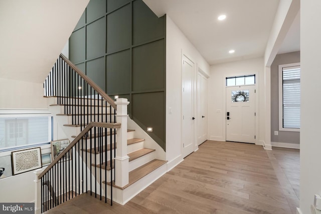 foyer with baseboards, wood finished floors, stairs, and recessed lighting