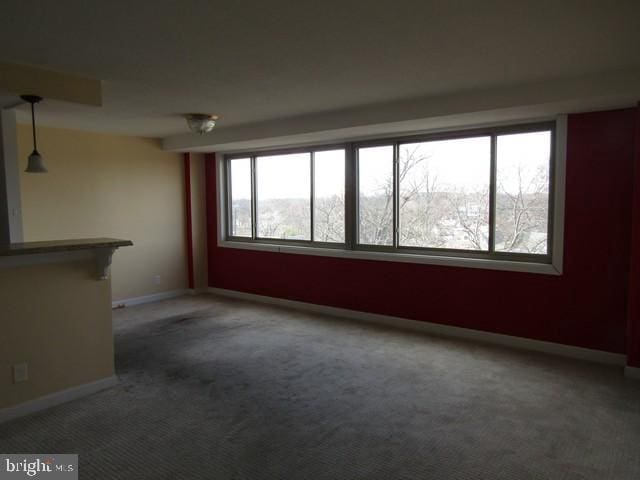 carpeted spare room with a dry bar and baseboards