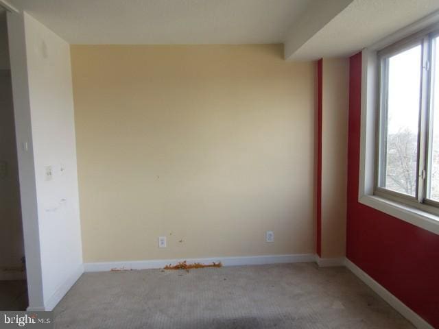 spare room featuring light carpet and baseboards