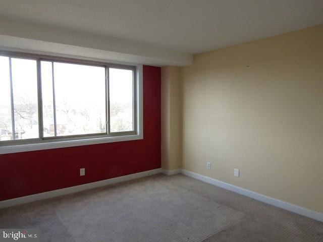 empty room featuring baseboards and carpet flooring