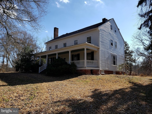 rear view of house featuring a lawn, covered porch, and a chimney