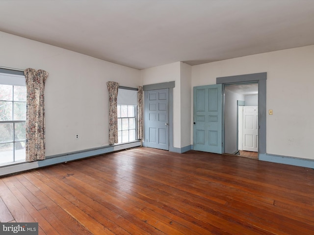 unfurnished bedroom with hardwood / wood-style floors, baseboards, multiple windows, and baseboard heating