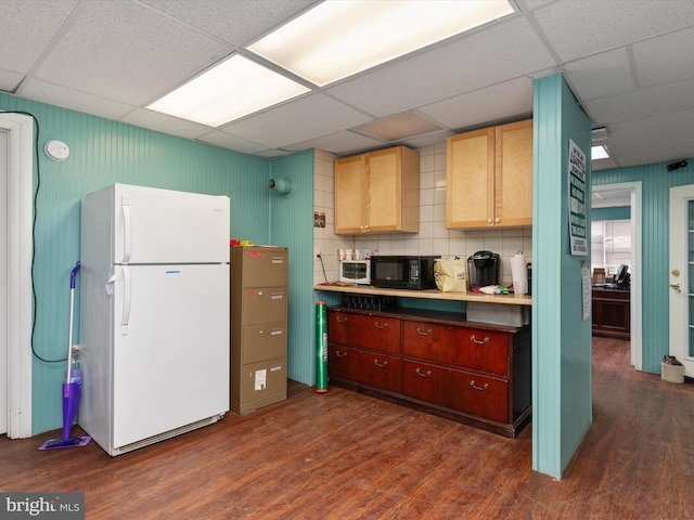 kitchen with decorative backsplash, black microwave, dark wood-style floors, a paneled ceiling, and freestanding refrigerator