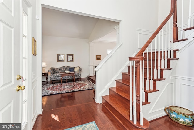 entryway with stairway, a decorative wall, dark wood-style floors, and wainscoting