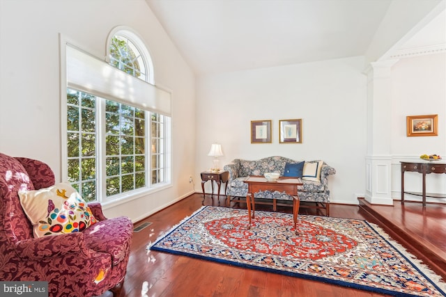 living area with lofted ceiling, decorative columns, wood finished floors, and a healthy amount of sunlight