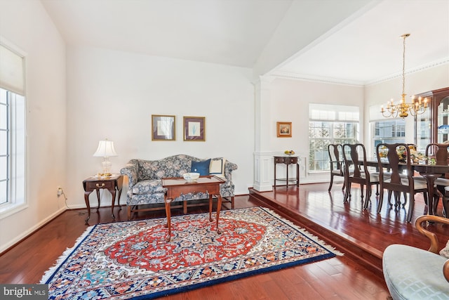 living area featuring hardwood / wood-style floors, an inviting chandelier, baseboards, and ornamental molding