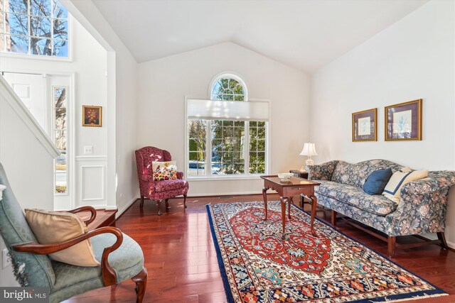 living room featuring hardwood / wood-style floors, baseboards, and vaulted ceiling