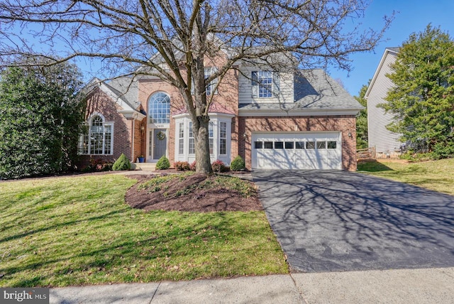 view of front facade with aphalt driveway, brick siding, and a front yard