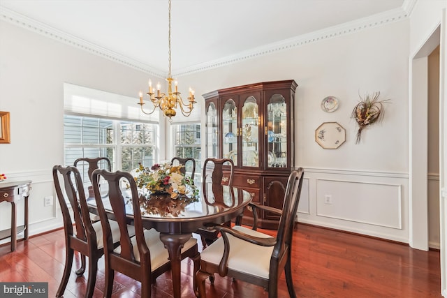 dining space featuring a wainscoted wall, a notable chandelier, dark wood-style floors, crown molding, and a decorative wall