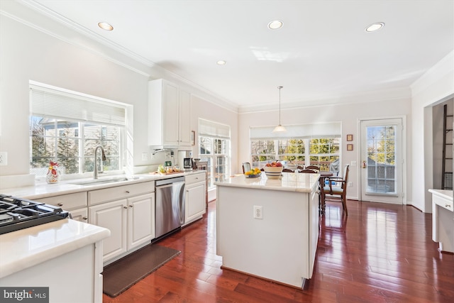 kitchen featuring dark wood finished floors, a sink, white cabinets, stainless steel dishwasher, and crown molding