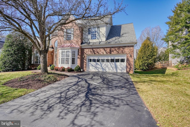 view of front of home featuring brick siding, fence, aphalt driveway, a front yard, and an attached garage