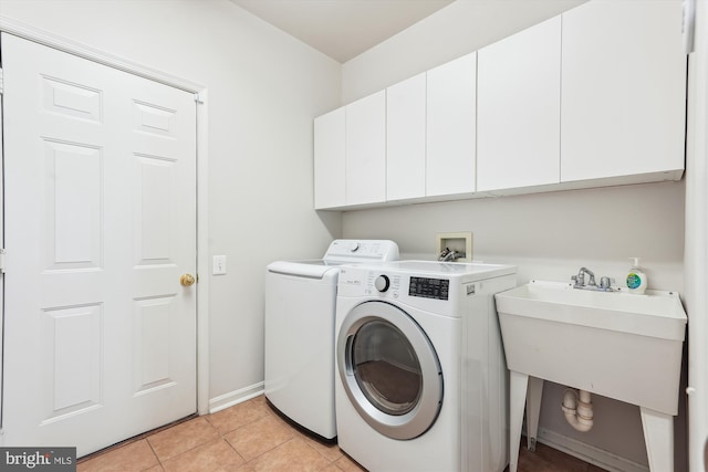 washroom featuring baseboards, light tile patterned flooring, cabinet space, a sink, and washer and clothes dryer