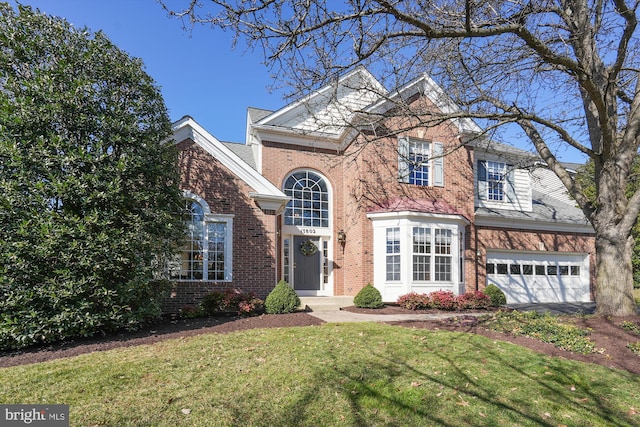 traditional-style house featuring driveway, brick siding, an attached garage, and a front yard