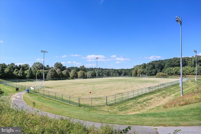 view of property's community featuring a rural view, a view of trees, and fence