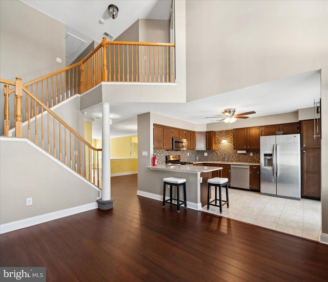 kitchen featuring light wood-type flooring, appliances with stainless steel finishes, a peninsula, and a ceiling fan