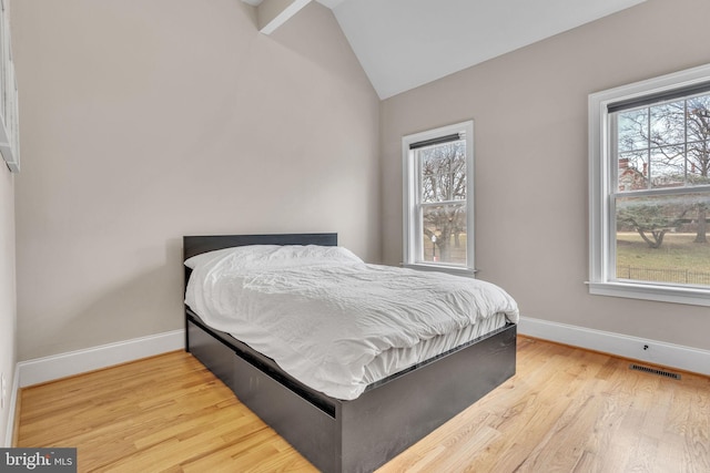 bedroom featuring vaulted ceiling, wood finished floors, visible vents, and baseboards