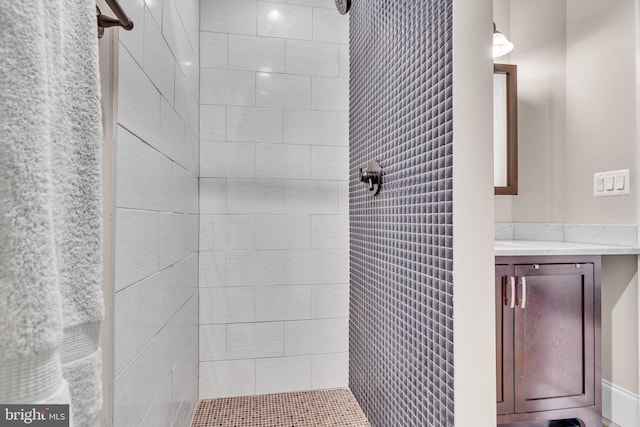 full bath featuring a tile shower and vanity