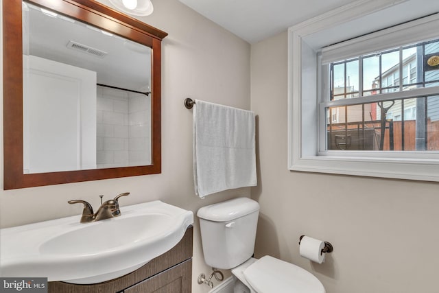 bathroom featuring toilet, vanity, and visible vents