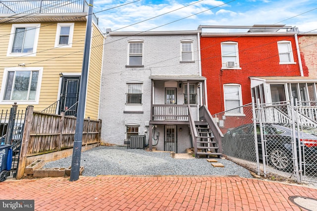 back of property featuring a sunroom, stairway, fence, central AC, and brick siding