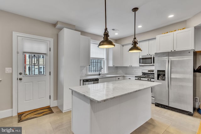 kitchen with a center island, tasteful backsplash, visible vents, appliances with stainless steel finishes, and a sink