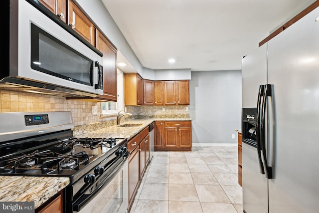 kitchen featuring light tile patterned floors, a sink, appliances with stainless steel finishes, decorative backsplash, and brown cabinetry