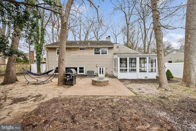 back of property featuring an outdoor fire pit, central air condition unit, fence, a sunroom, and a patio area