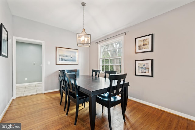 dining space with a chandelier, baseboards, and light wood-style floors