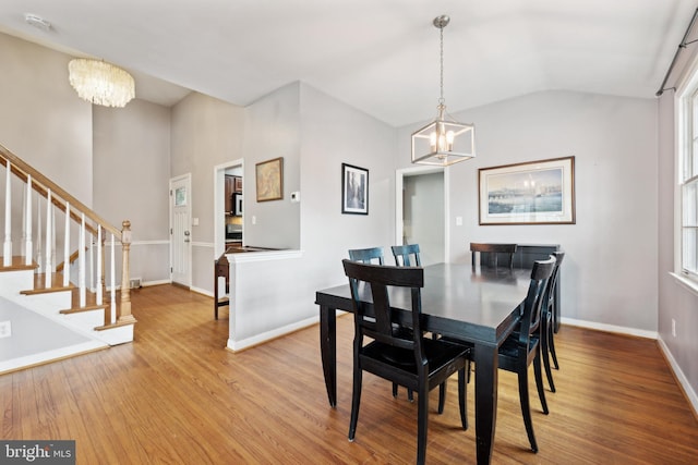 dining room featuring stairs, wood finished floors, baseboards, and an inviting chandelier