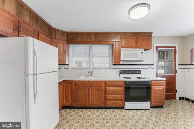 kitchen featuring white appliances, a sink, light countertops, tile walls, and brown cabinets