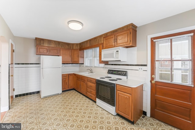 kitchen featuring a sink, white appliances, a wealth of natural light, and light countertops