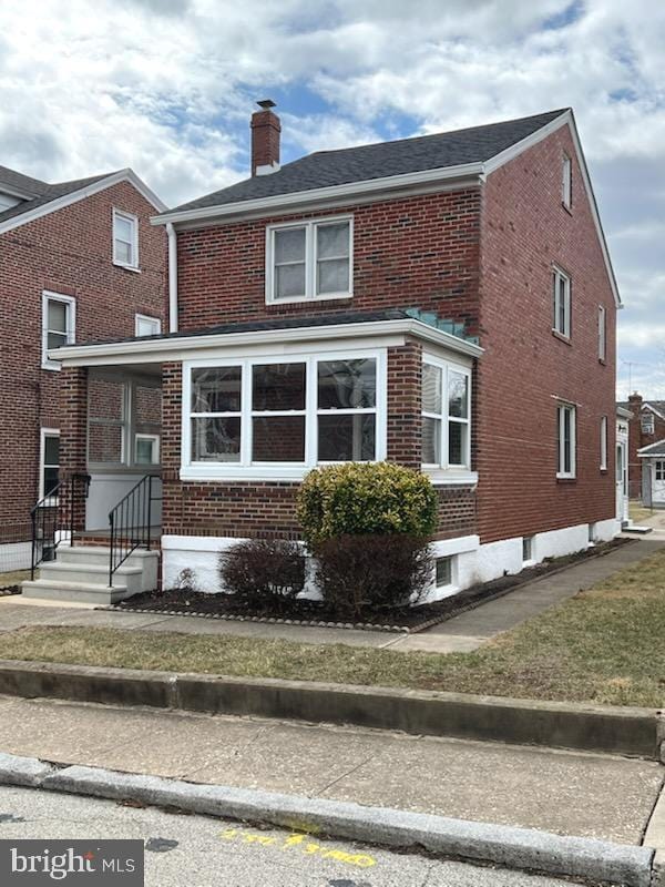 back of house with brick siding, a chimney, and entry steps