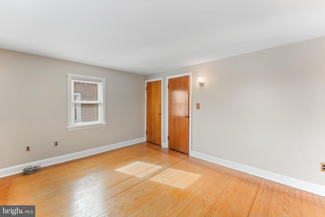 unfurnished room featuring baseboards and light wood finished floors