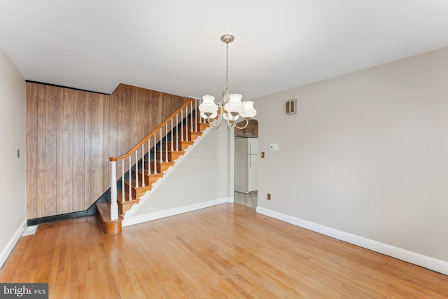 interior space featuring an inviting chandelier, stairway, wood finished floors, and visible vents